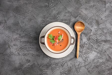 Spanish cold gazpacho soup with tomatoes, pepper, garlic and fresh herbs in a dark plate on black background top view with copyspace. Vegetarian food for health. Flat lay.の写真素材