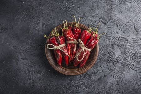 Spicy chili on a dark background in ceramic plates, flatlay. Used as an ingredient for harissa,...