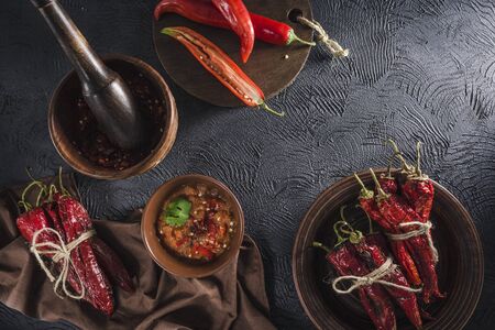 Spicy chili on a dark background in ceramic plates, flatlay. Used as an ingredient for harissa, ajika, muhammara. East and middle East kitchen.の写真素材