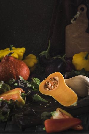 Fresh harvest of vegetables from pumpkin, eggplant, pepper, lettuce, red onion and squash on a dark wooden background close-up with a copy spaceの写真素材