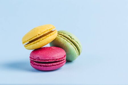 Colorful macaroons on a blue background, close-up, Flatley with copy space. Dessert with melon, lemon and raspberry flavor. Artの写真素材