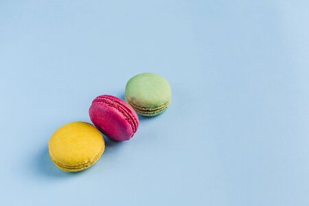 Multicolored macaroons on a blue background, top view, Flatley with copy space. Dessert with melon, lemon and raspberry flavor. Artの写真素材