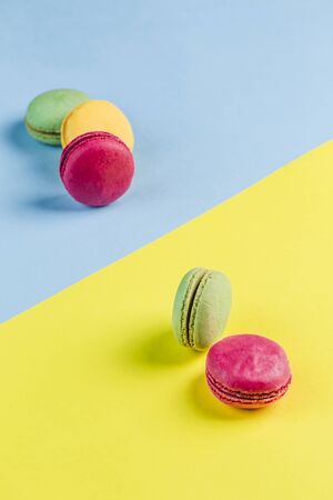 Multicolored macaroons on a blue and yellow background, top view, Flatley with copy space. Dessert with melon, lemon and raspberry flavor. Artの写真素材