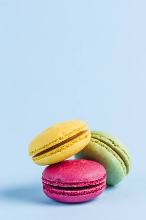 Colorful macaroons on a blue background, close-up, Flatley with copy space. Dessert with melon, lemon and raspberry flavor. Artの写真素材