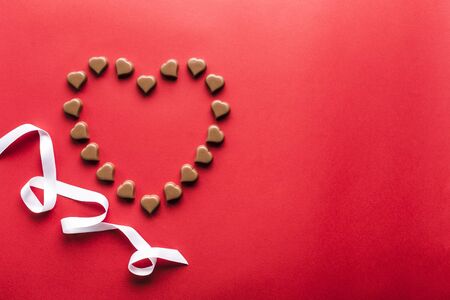 Heart shaped chocolates on red background for Valentine's day top view flat lay copyspaceの写真素材