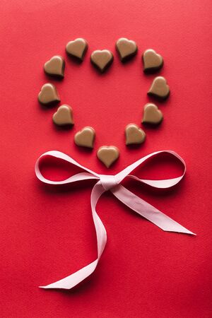Heart shaped chocolates on red background for Valentine's day top view flat lay copyspaceの写真素材
