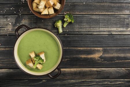 Broccoli cream soup with croutons in a plate on a wooden black background.  Concept of healthy nutrition. Top view with copy space. Horizontal orientation.の写真素材