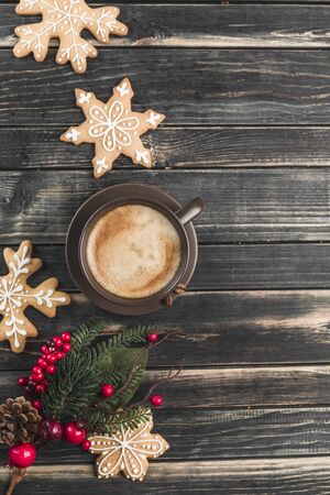 A Cup of coffee with foam on a dark wooden background with gingerbread in the form of snowflakes. New year and Christmas mood. Energy hot drink. The view from the top. Flat lay.の写真素材