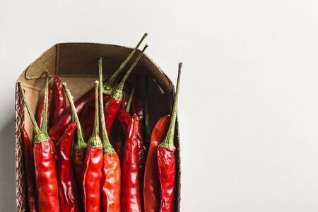 lots of hot chili peppers in a box top view on a white background with a copy spaceの写真素材