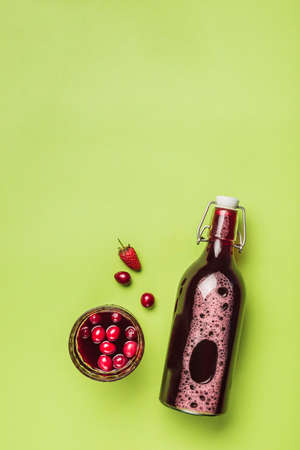 The concept of a summer refreshing drink from red berries: berry Morse of fresh strawberries and cranberries is a great drink to quench your thirst on a green background with a copy space. Top view. Vertical orientation.の写真素材
