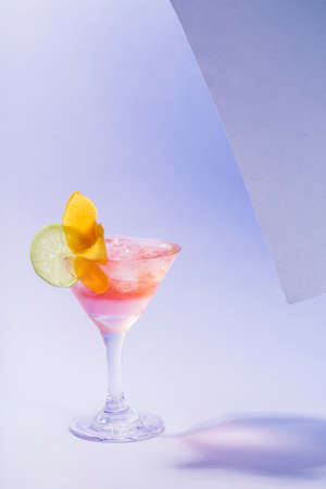 Alcohol Margarita cocktail with ice frappe, a slice of lime and orange zest on a tropical background with copyspace. Vertical orientation.の写真素材