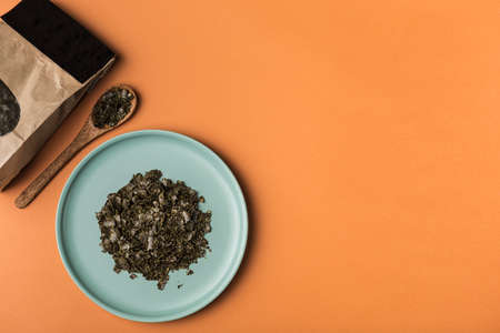 Hemp flakes in a flat plate on an orange background. flatlay with copy space. Cannabis food concept. Horizontal orientation.の写真素材