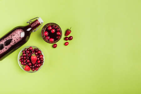 The concept of a summer refreshing drink from red berries: berry Morse of fresh strawberries and cranberries is a great drink to quench your thirst on a green background with a copy space. Top view. Horizontal orientation.の写真素材