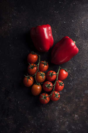 Fresh spring paprika and cherry tomatoes on a dark background. Top view with a copy space. Vegetables for healthy nutrition. Vertical orientation.の写真素材