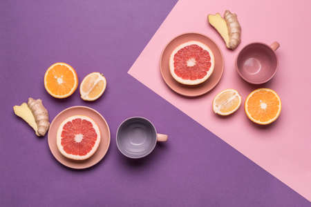 Lemons, oranges, grapefruit and ginger on a flat plate on a purple-pink colored background. Concept of healthy nutrition and vitamins. Flat lay with copy space. Horizontal orientation.の写真素材