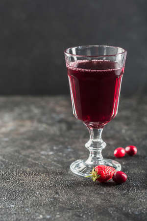 The concept of a summer refreshing drink from red berries: berry Morse of fresh strawberries and cranberries is a great drink to quench your thirst on a black background with a copy space. Vertical orientation.の写真素材