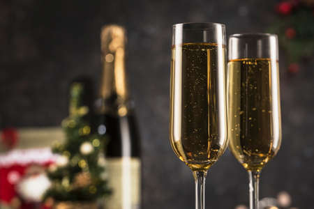 New year 2021 - two glasses of champagne on a dark background with bokeh from garlands. Classic alcoholic drink for a new year's holiday atmosphere. Horizontal orientation with a copyspace.の写真素材