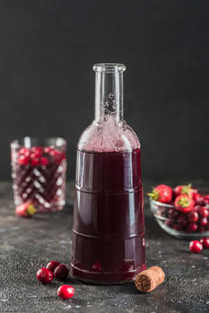 The concept of a summer refreshing drink from red berries: berry Morse of fresh strawberries and cranberries is a great drink to quench your thirst on a black background with a copy space. Vertical orientation.の写真素材