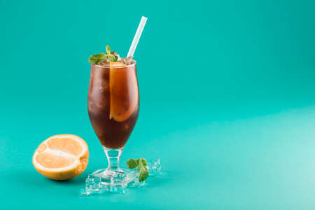 Refreshing iced coffee with orange and mint in a glass with a tube on a bright background. Coffee drink to quench your thirst on a hot day. Horizontal orientation.の写真素材