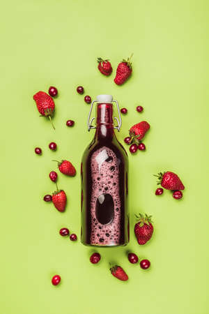 The concept of a summer refreshing drink from red berries: berry Morse of fresh strawberries and cranberries is a great drink to quench your thirst on a green background with a copy space. Top view. Vertical orientation.の写真素材