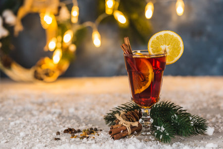 New year's atmosphere-warming alcoholic drink mulled wine with cinnamon and orange slices on the background with spruce branches and bokeh garlands. Close up. Horizontal orientation.の写真素材