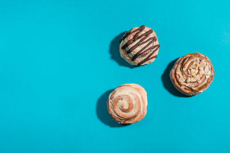 Three Cinnabon buns on a blue background with hard shadows. Side view with copy space. Horizontal orientation. American classic bun.の写真素材