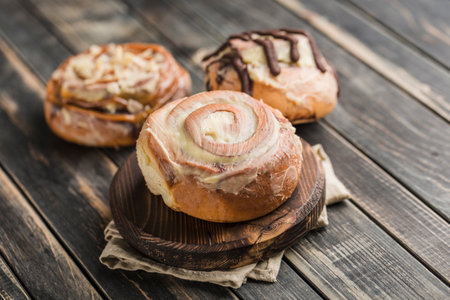 Three Cinnabon buns on a wooden Board with a napkin on a dark background. Close-up with copy space. Horizontal orientation. American classic bun.の写真素材