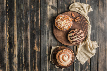 Three Cinnabon buns on a wooden Board with a napkin on a dark background. Top view with copy space. Horizontal orientation. American classic bun.の写真素材