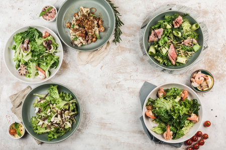 Several dishes with salads from fresh vegetables with fish and meat in different bowls with the flow from the chef on a light background, top view with copyspace. flat lay. Restaurant food.の写真素材