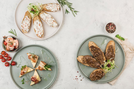 Bruschetta with different toppings of meat and fish with sauces on the plates with the flow from the chef on a light background, top view with copyspace. flat lay. The concept of Breakfast. Restaurant food.の写真素材