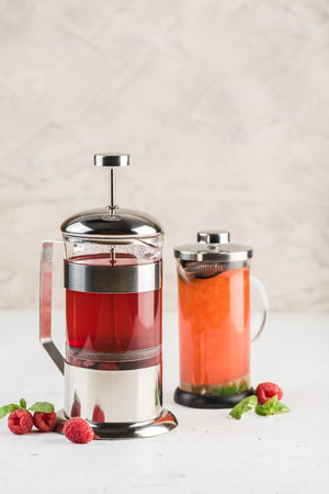 French press with tea from different berries and sea buckthorn on a light background. Side view with copyspace. Restaurant food.の写真素材