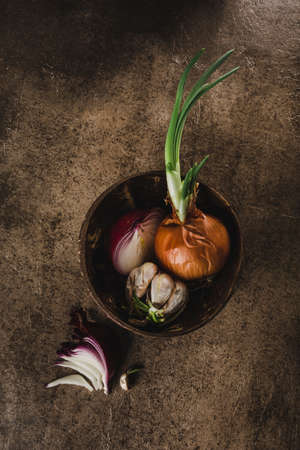 Sprouted onions grown at home with red onion slices and sprouted garlic in a wooden bowl on a dark background with a copy space for the text top view. Raw food, eco-friendly product.の写真素材