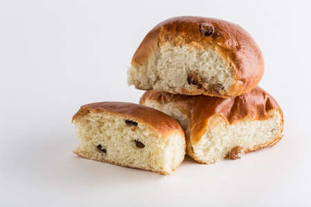 Two sweet buns with raisins with a cut piece on a white background, isolated. Close-up with a copy...