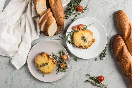 Baked meat and cheese on a plate with French bread baguette with herbs and cherry tomatoes on a light background. Top view with a copy space for the text. The restaurant's menu. Horizontal orientation.の写真素材