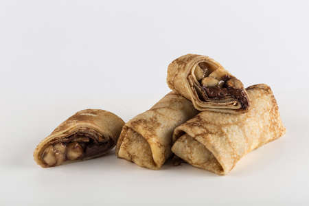Several pancakes with banana filling with chocolate on a white background close-up with a copy space for the text, isolated. Traditional food for the Maslenitsa holiday. Horizontal orientation.の写真素材