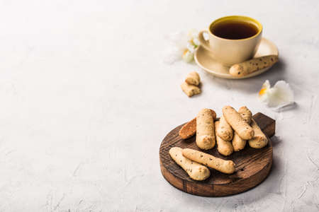 Long shortbread cookies on a dark wooden board with a cup of tea on a light background. The concept...