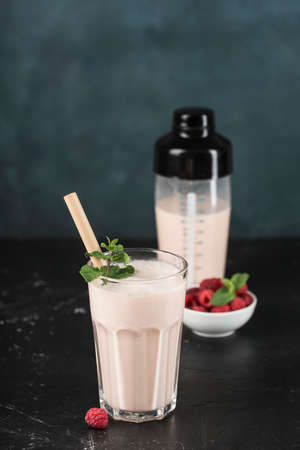 Lassie drink with raspberries in a glass with mint and a cocktail shaker on a dark background. Vertical orientation. Indian traditional refreshing drink.の写真素材