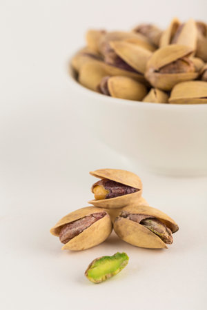 Pistachios close-up on a light background and in a white bowl. A natural product for the diet. Side...