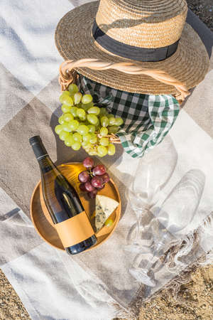 Summer picnic on the beach with wine, cheese and grapes. Top view with a copy space. Vertical orientation.の写真素材