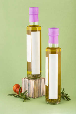 Olive oil with rosemary spices in a glass bottle with a place for the label on a light green background. Traditional European dressing for salads and cooking various dishes. Side view with a copy spaceの写真素材