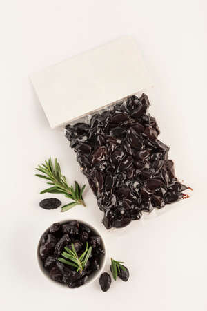Black dried olives in vacuum packaging with a place for the label on a light background. Top view with a copy space for text. Vertical orientation.の写真素材