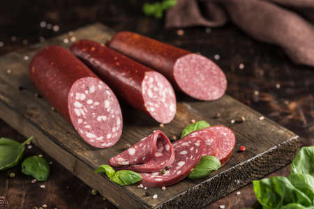 A set of grainy sausage made of horse meat and chicken on a wooden board with a dark background....