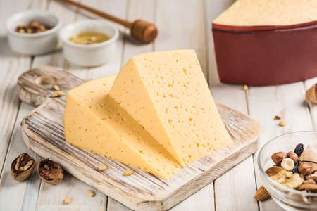 Traditional cream cheese cut into pieces on a wooden board. Dark wooden background. Side view close-up.の写真素材