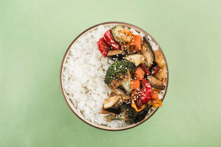 A bowl with grilled rice and vegetables on a light green background. Asian food. horizontal orientation. top view.の写真素材