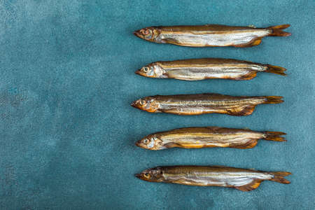 A few smoked capels on a blue background. Fish as an appetizer for beer. Horizontal orientation, top view with a copy space for text.の写真素材
