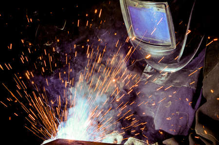 Welder on the production of weld metal. Sparks fly smoke