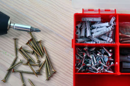 Electric screwdriver and screws on a wooden table.