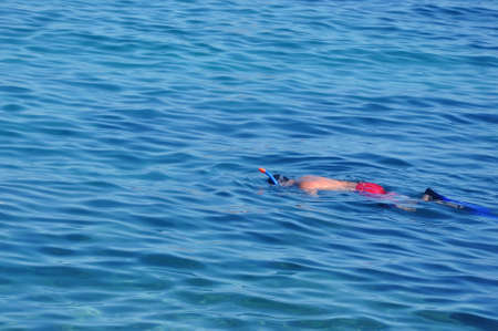 A man in a mask and snorkel diving into the sea wave.の写真素材