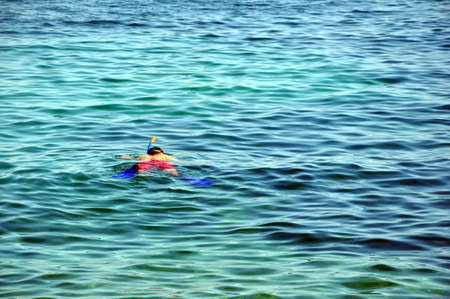 A man in a mask and snorkel diving into the sea wave. Travel and summer vacation on the sea.の写真素材