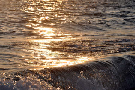 Tropical sunset background. Beautiful colorful ocean wave breaking closing near sand beach